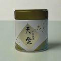 Tea canister with a green label on a white fabric background