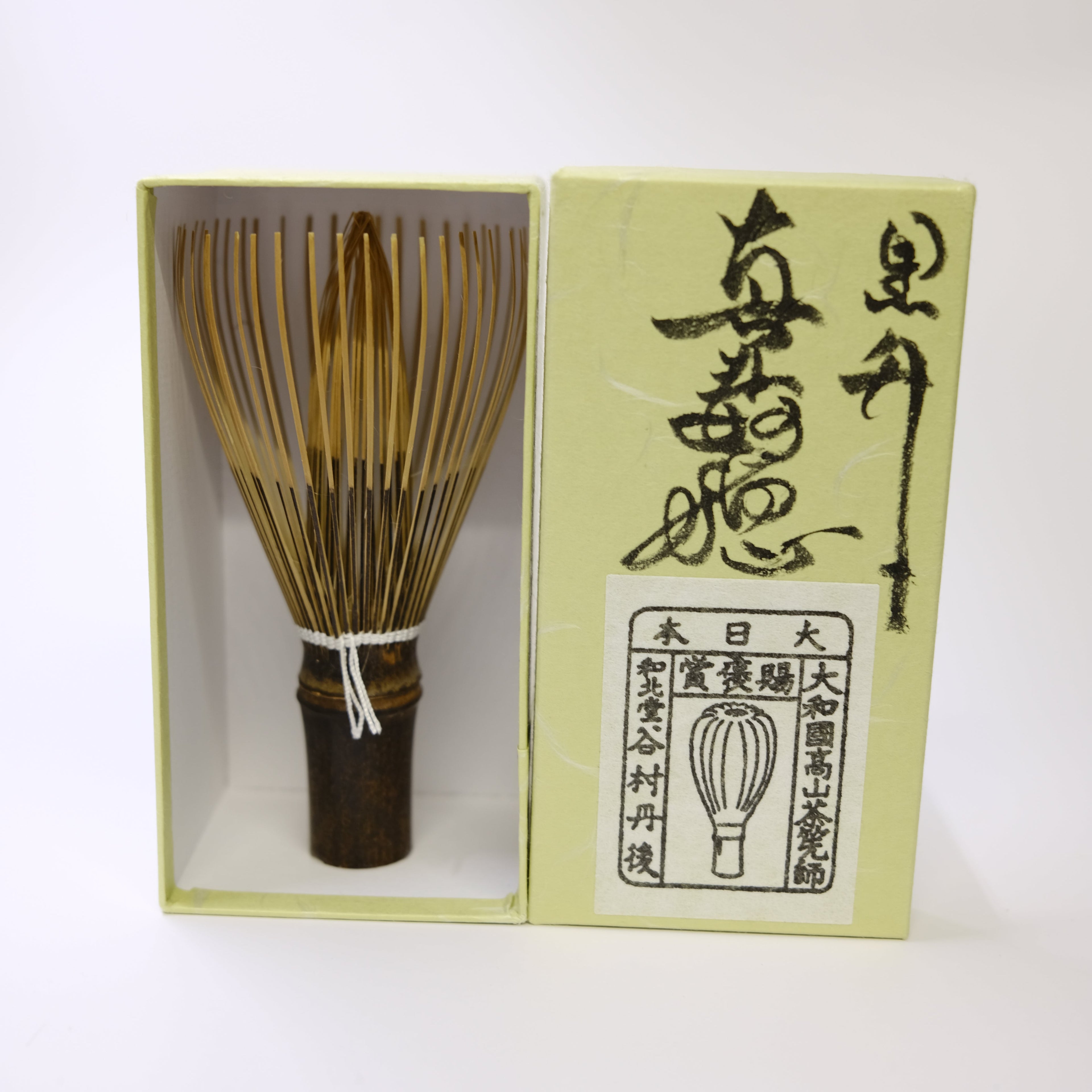 Bamboo whisk with wooden handle in a box on a white background