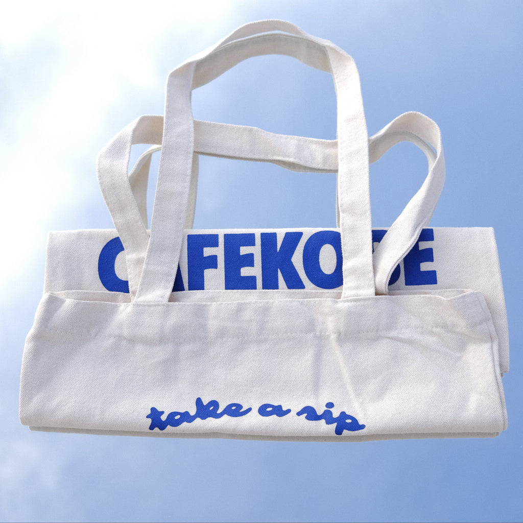 White tote bag with blue text on a reflective surface
