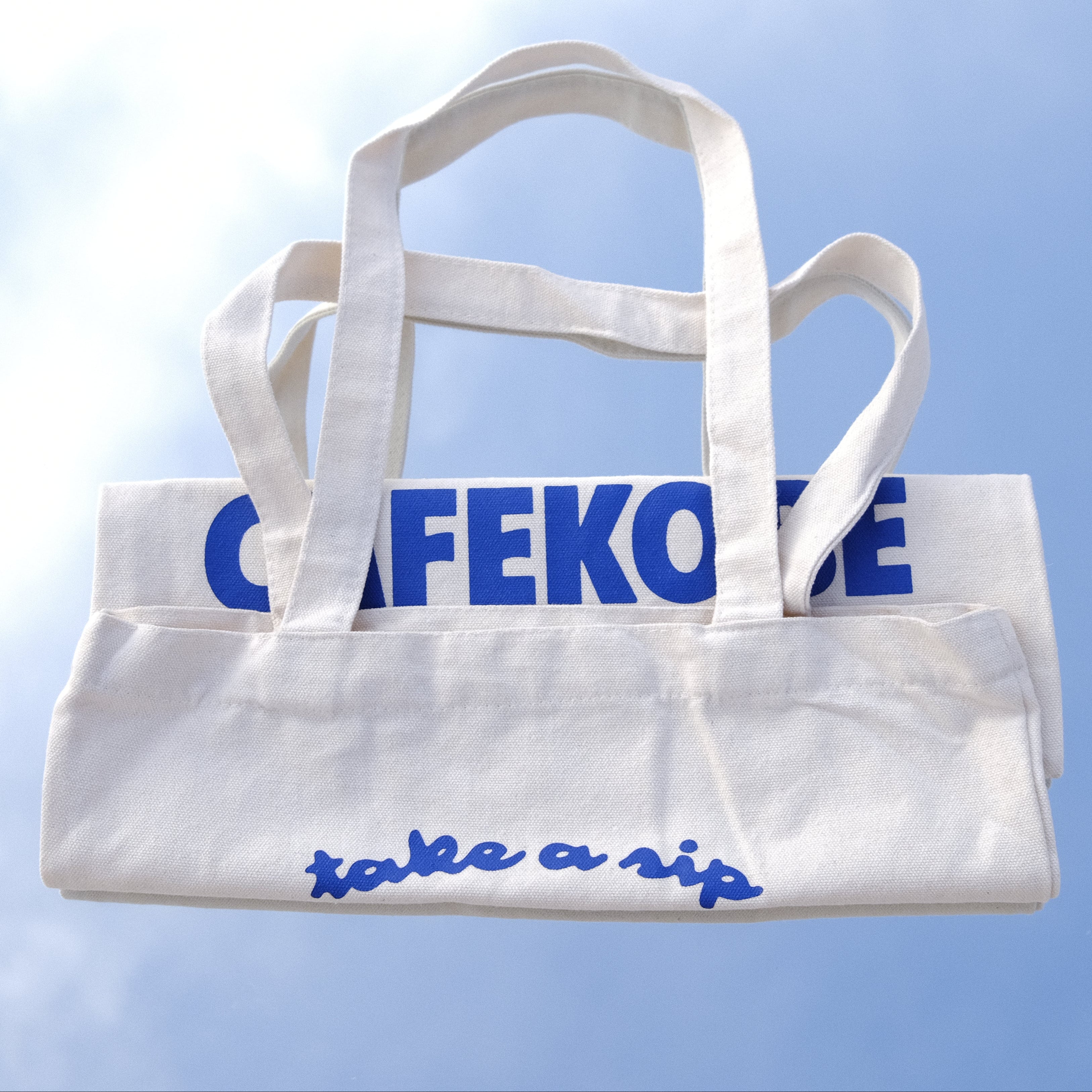 White tote bag with blue text on a reflective surface
