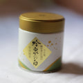 Small cylindrical container with a gold lid on a white background